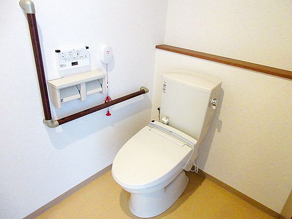 呼び出しボタンや手すり、トイレットペーパーホルダーが付いた洋室のトイレ。スペースも広い。