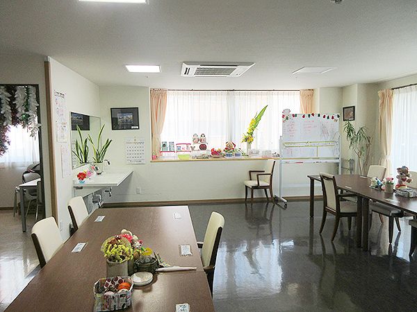 木製のダイニングテーブルには白い椅子がセットされ、奥には車いす対応の洗面所がある。