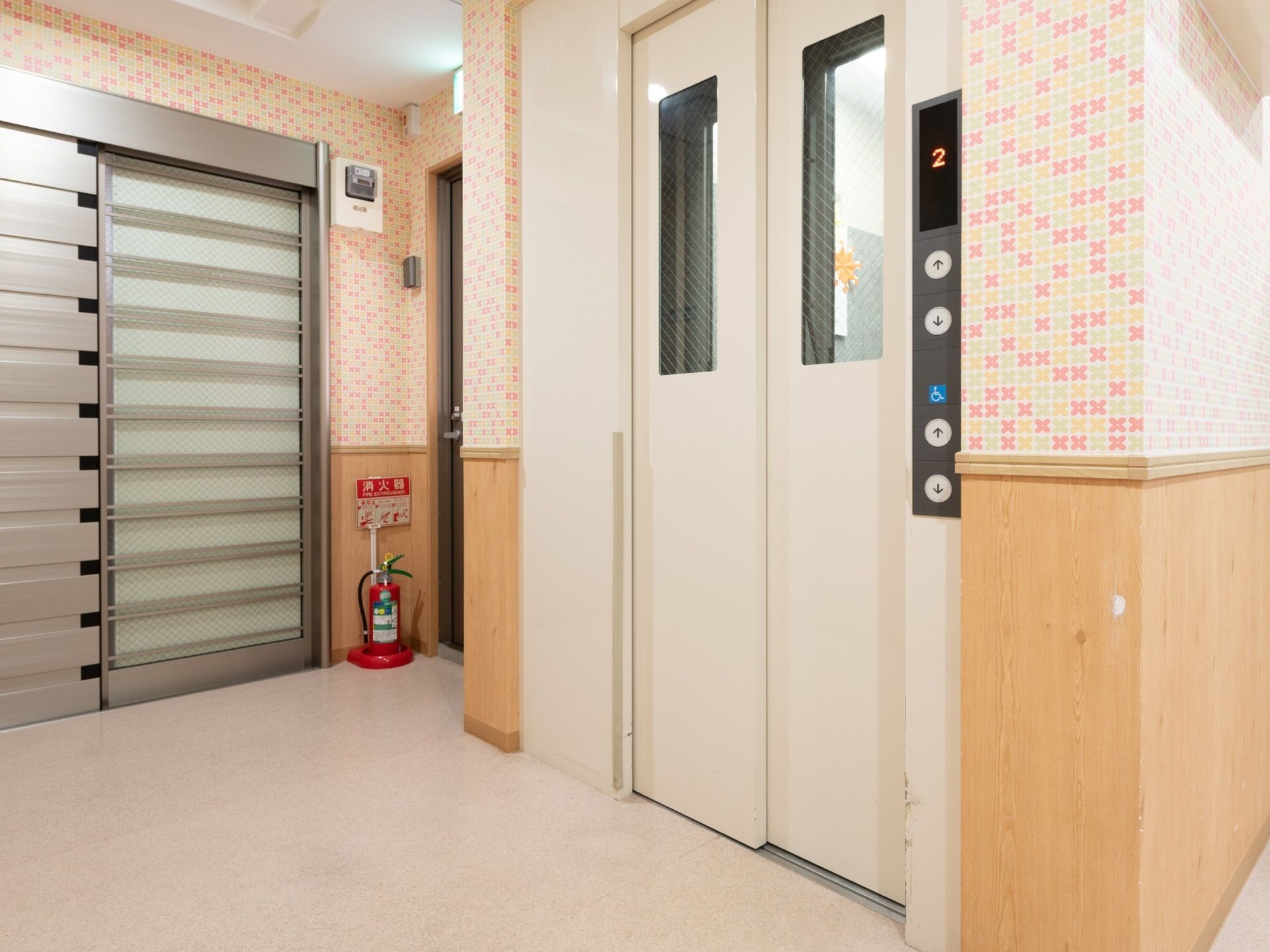 廊下を曲がったところにエレベーターが設置されている。車椅子用ボタンが低い位置にあるため、車椅子でも押しやすい。
