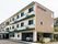 3階建ての建物は横に長く、1階部分の一部が駐車場となっていて車が止められている。玄関先には車寄せもある。