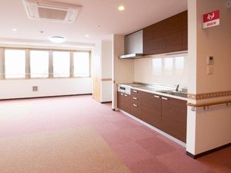 オール電化のキッチンが付いた共有スペースは広く、まだ家具などは置かれていない。大きな窓が付いている。