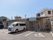 平屋建ての建物の手前に駐車場があり、車が停まっている。舗装された地面に白線で駐車スペースが記されている。