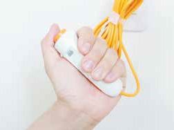 オレンジのコードが付いた緊急通報装置のボタンを片手でしっかり通している様子。コードはまとめられている。