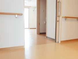 スライド式のドアが付いた居室と廊下の間に段差はなく、日当たりのいい居室内には家具はなく、廊下には手すりがある。