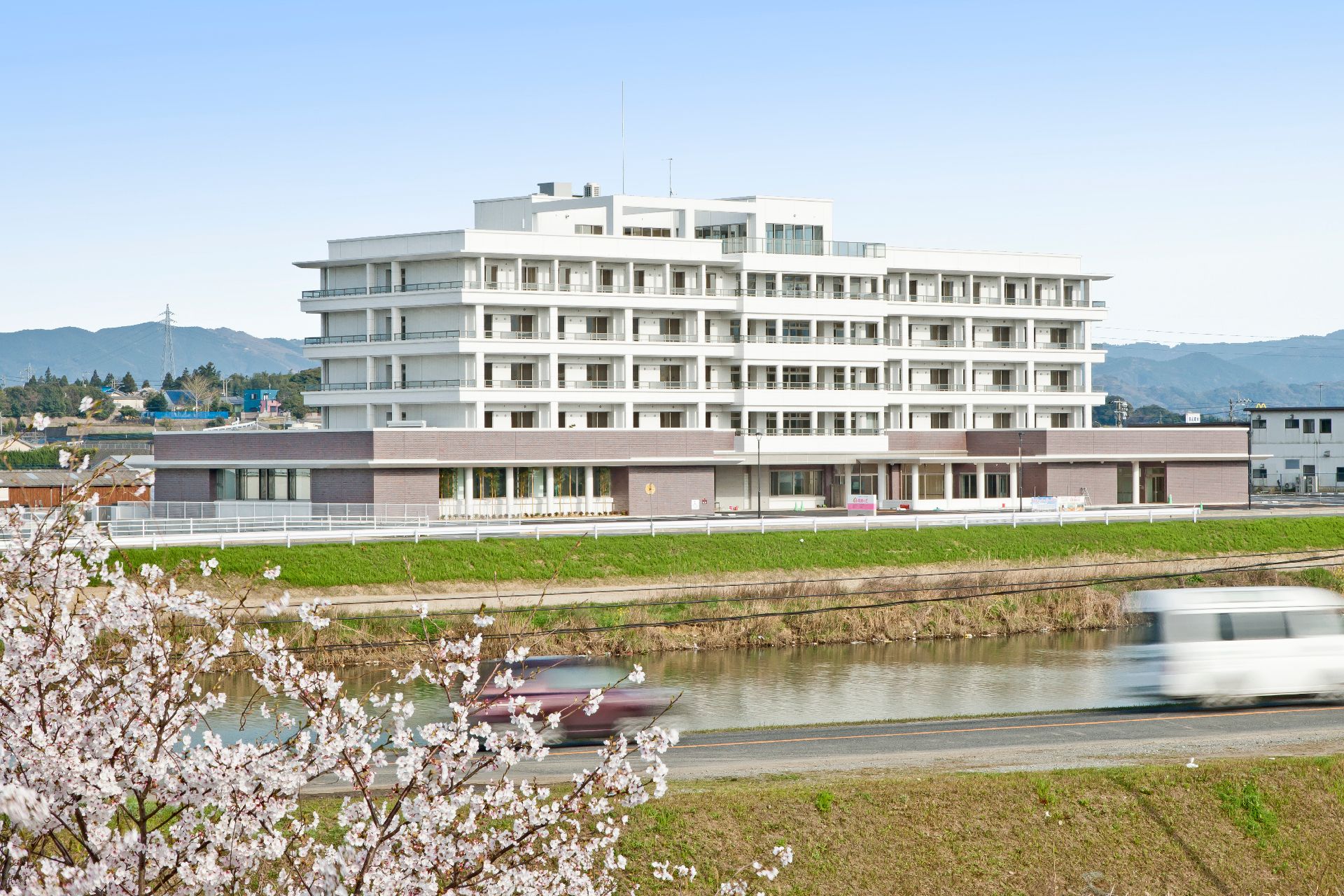 広々としたフローリングの共有スペースには木製のテーブルセットが並べられ、大きな窓があり明るい雰囲気。