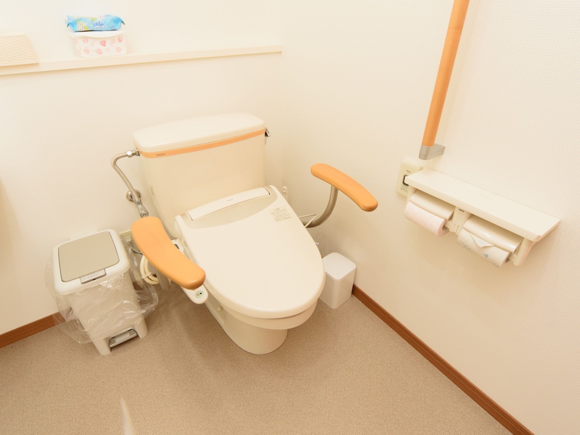 壁や便器の左右には木の手すりが付いている。便器周りのスペースが広く、明るく清潔感がある。トイレットペーパーが２つセットしてある。