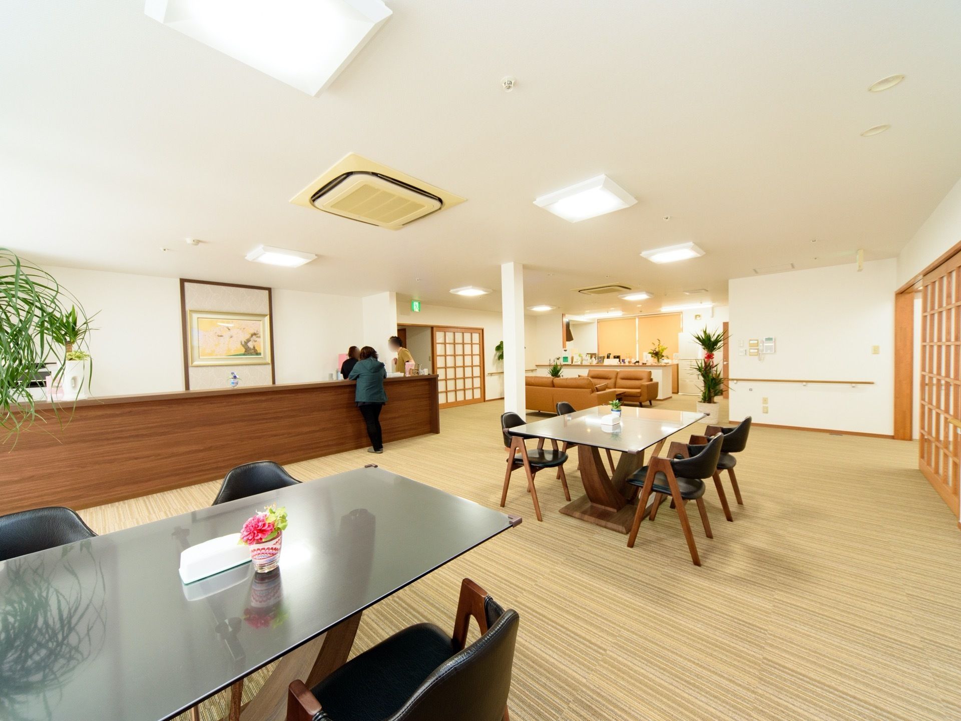 広い部屋にテーブルやソファが置いてある。格子の扉や木のカウンターが和風なイメージになっている。テーブルの間隔は広くなっている。