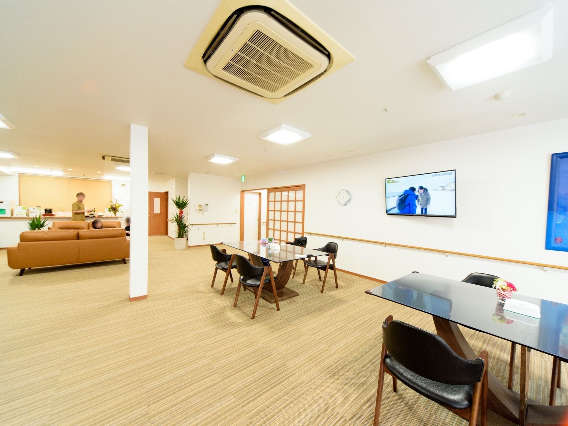 広い部屋にテーブルやソファが置いてある。テレビは壁に掛けてあり、どこからも見やすくなっている。ライトがたくさんあり、明るい。