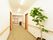 明るい通路には観葉植物が置いてある。床は絨毯で、壁には手すりがあり、安全に歩行できる。壁と天井が白で統一されていて明るい。