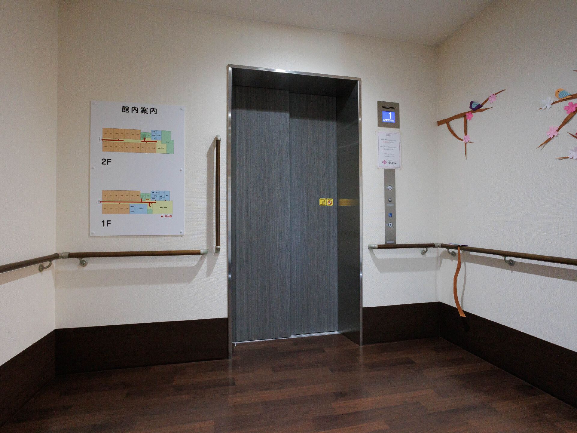 屋外で笑顔で過ごしている車いすの高齢女性。周りには付き添いの高齢男性と若い男女のスタッフがいる。