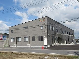 2階建ての建物は玄関に車寄せが付き、広い駐車場もあり、外壁には施設名が書かれている。