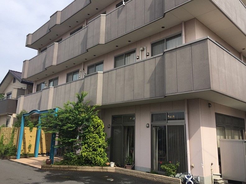すぐそばに街路樹がある茶色い外壁の3階建て建築物