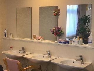 大きな鏡がそれぞれについた洗面所が３つ並んでいる。洗面所は車いす対応でソープなども置かれている。