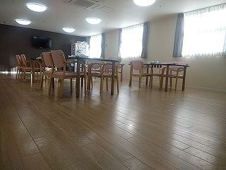木製のダイニングテーブルが複数置かれた食堂はフローリングのフロアで広く、大きな窓がたくさんついている。