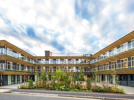 3階建ての建物はコの字型で中央に緑が植えられ、それぞれのフロアにベランダが付いている。