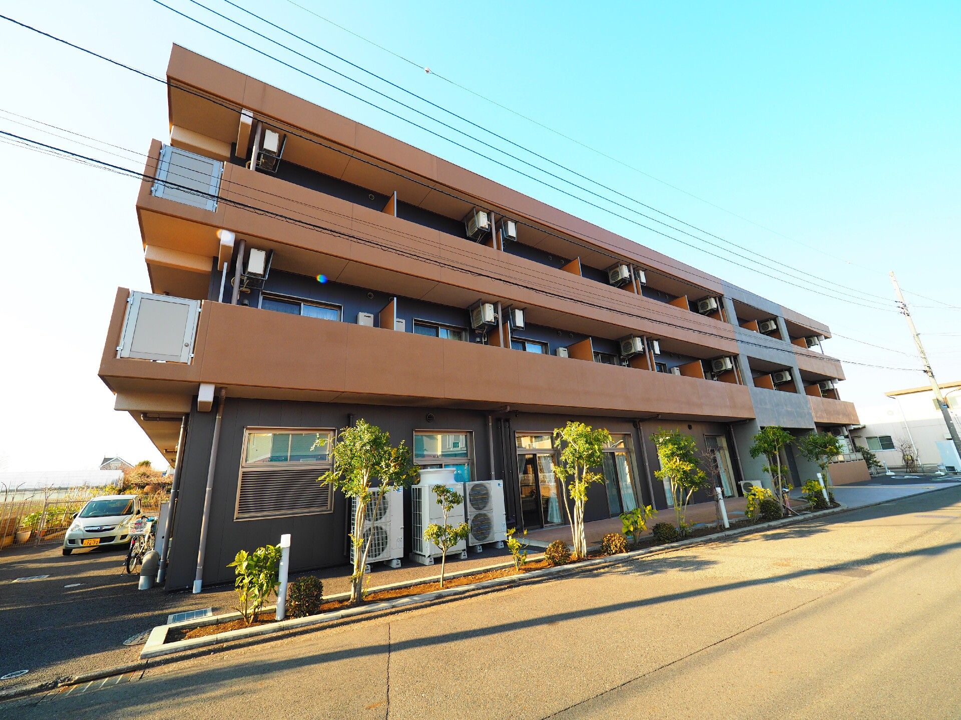 道路に面して建っている地上3階建ての施設と、建物前に植えられた木々