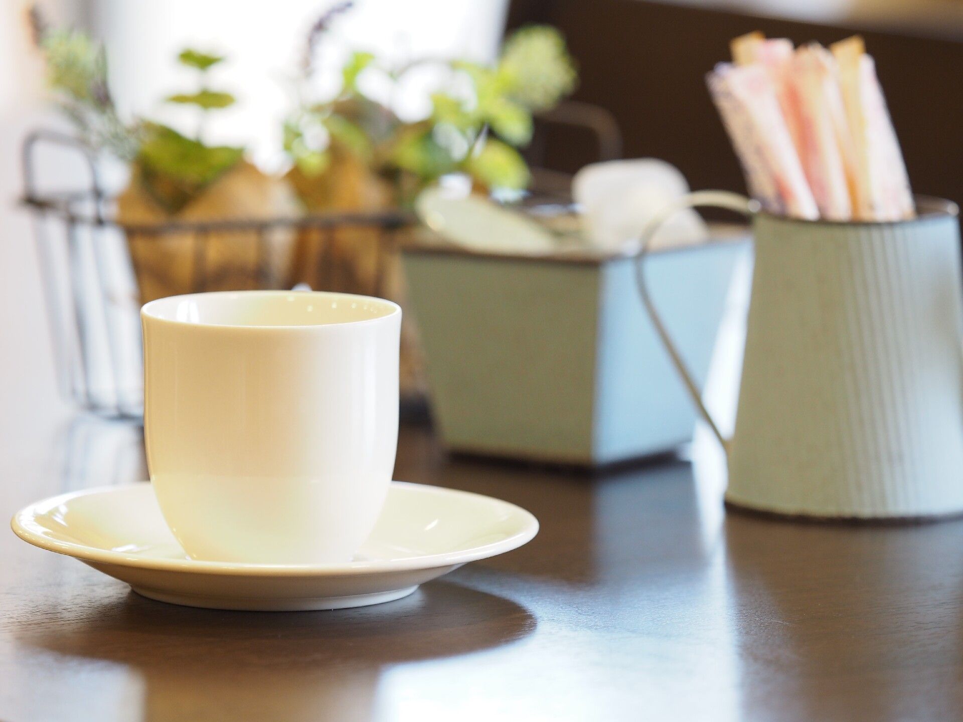 テーブル上にある白い磁器製のコーヒーカップとソーサー、スティックシュガー
