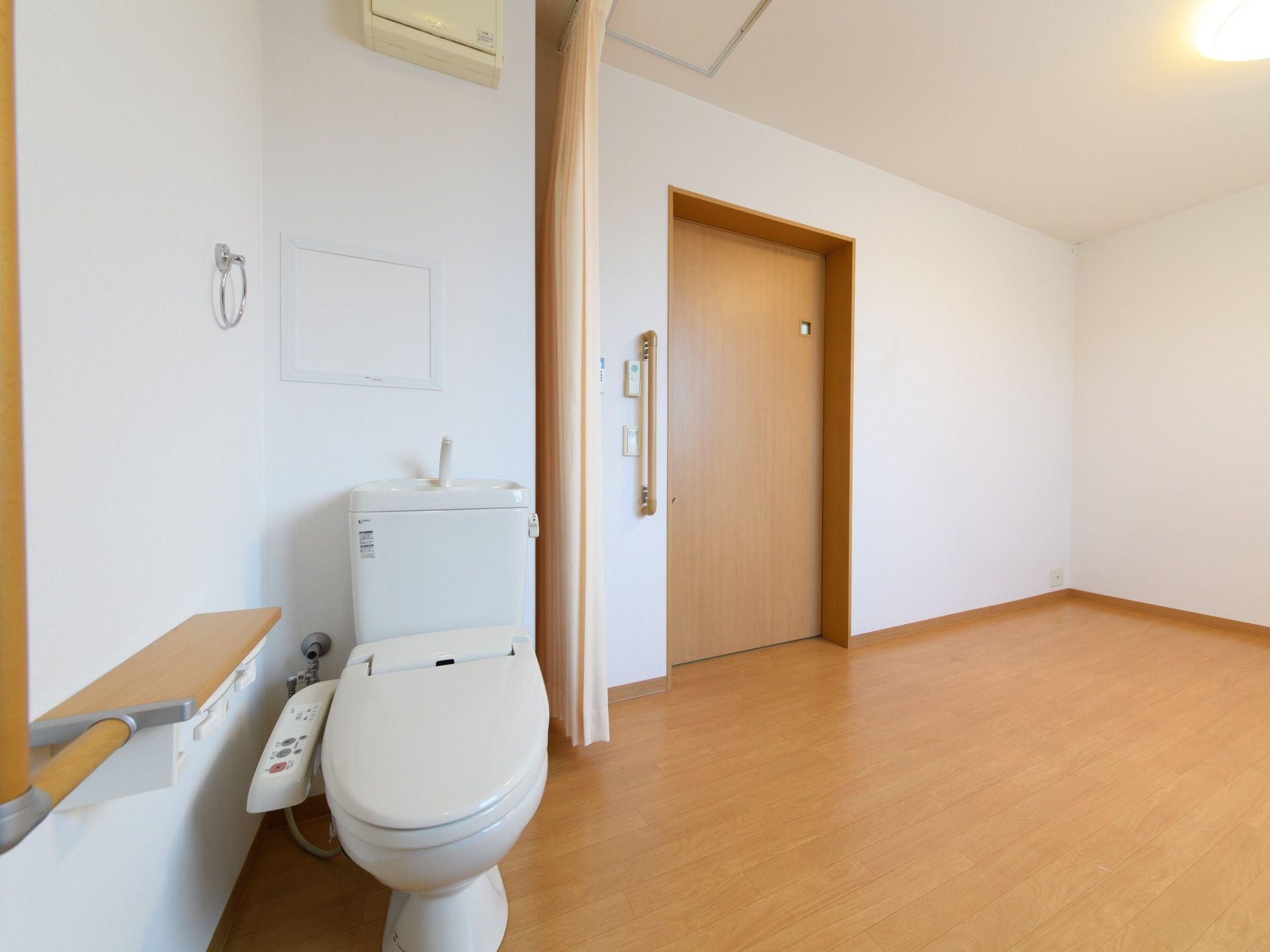 居室は広々としたスペースのフローリング敷になっている。入口の脇にはトイレスペースが設けられており、扉はカーテンタイプになっている。