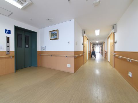 居室前の廊下から壁の手すり沿いの先に完備されているエレベーター