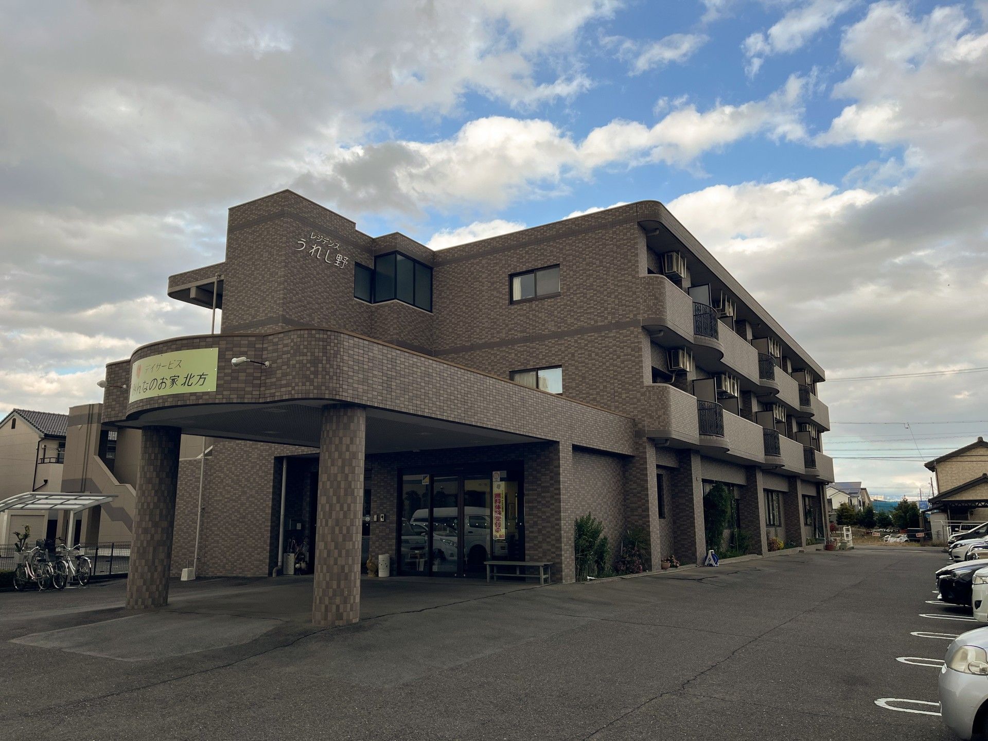 グレー系の３階建ての建物は各フロアにベランダがあり、玄関には車寄せが付き、日当たりのいい場所に建っている。