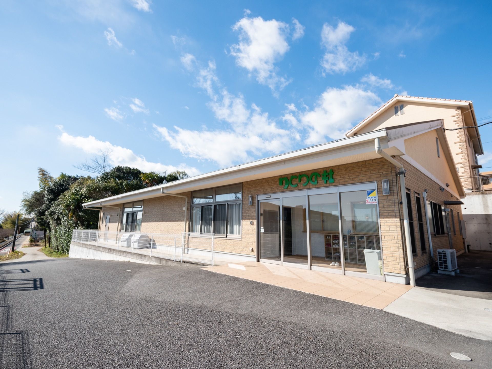 オレンジ系の平屋建ての建物である。玄関は間口の広いガラス張りの自動ドアである。中の様子が分かるので安心感がある。