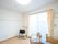 白を基調とした、さわやかな心地よさがある居室。液晶テレビや椅子があり、LEDライトが部屋を明るく照らしている。