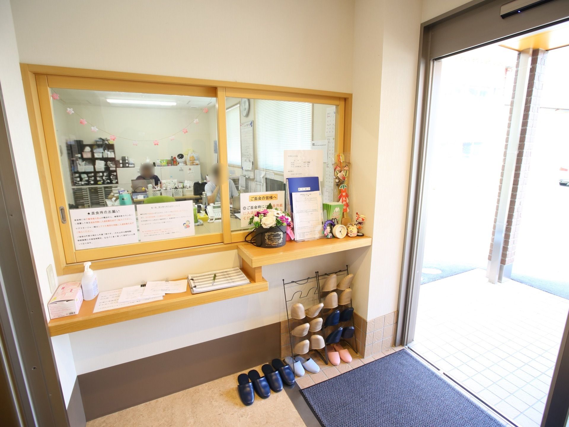 受付カウンターの上には展示品や入場者名簿が置かれている。カウンターの下にはスリッパが用意されている。