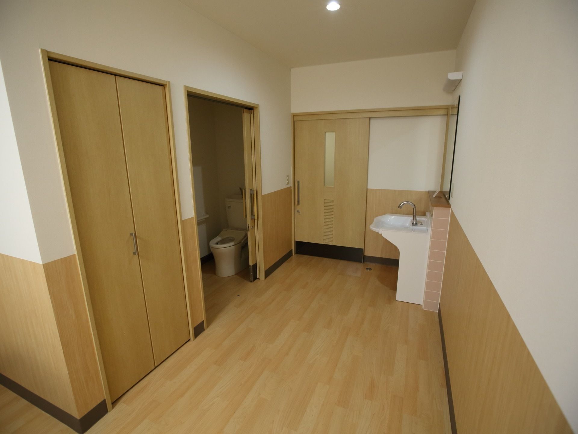 トイレと手洗い場が見えている。トイレの横には収納が設けられている。トイレと入り口の扉は引き戸になっている。