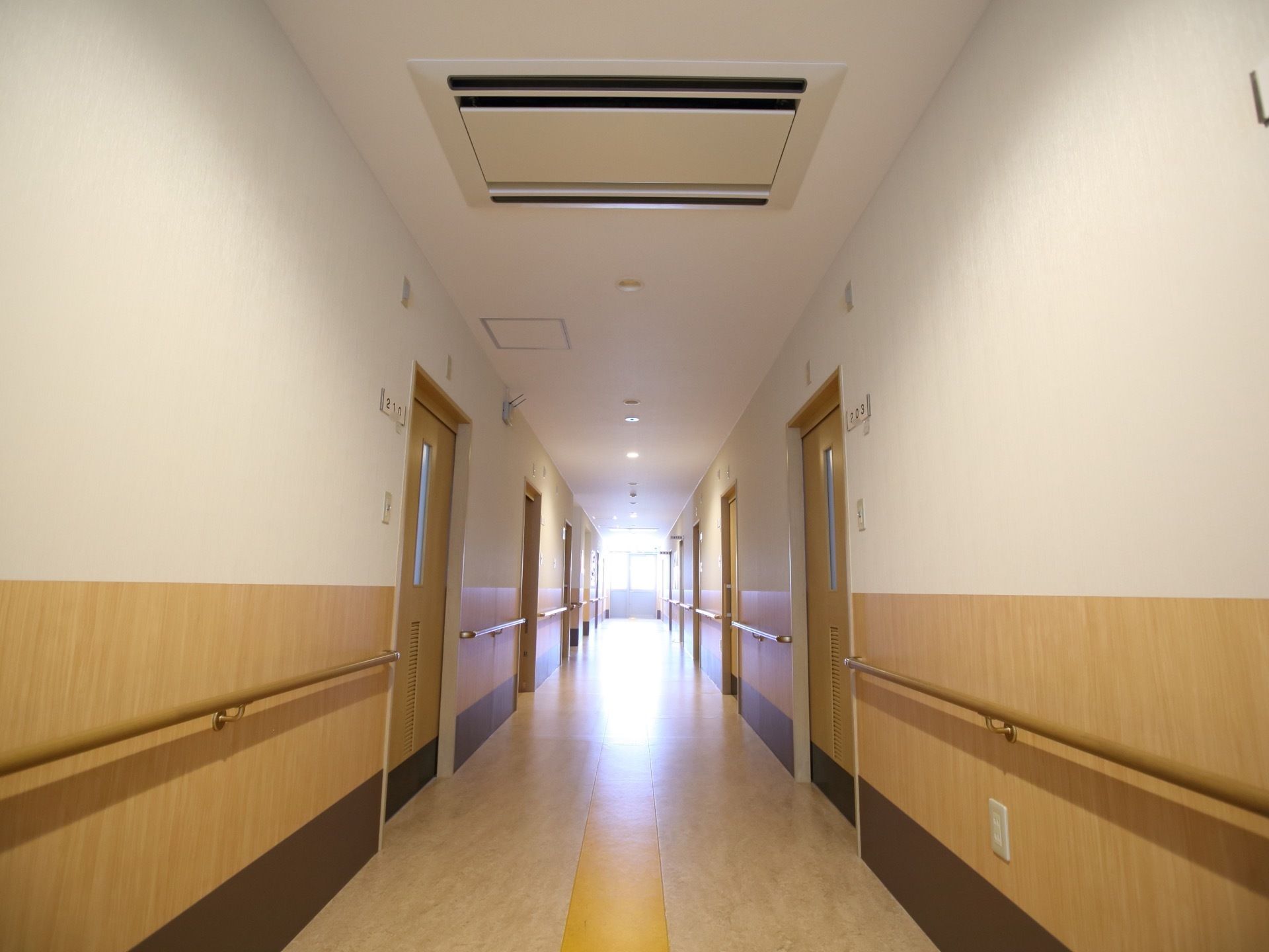 居室の扉は大きな引き戸になっており、その横には番号が書かれたプレートが貼られている。天井にはエアコンが設置されている。