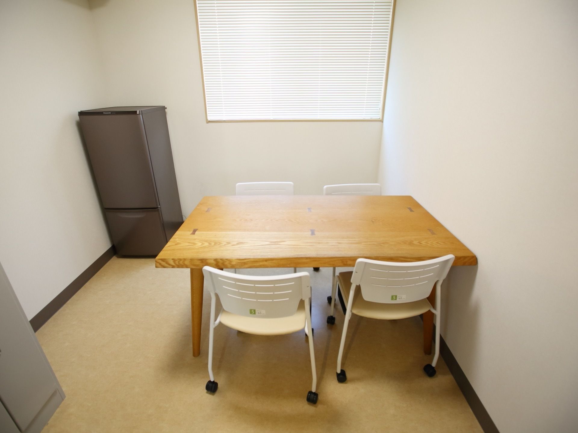 部屋の中央にはテーブルがあり、キャスター付の椅子が４脚置かれている。冷蔵庫とロッカーが用意されている。