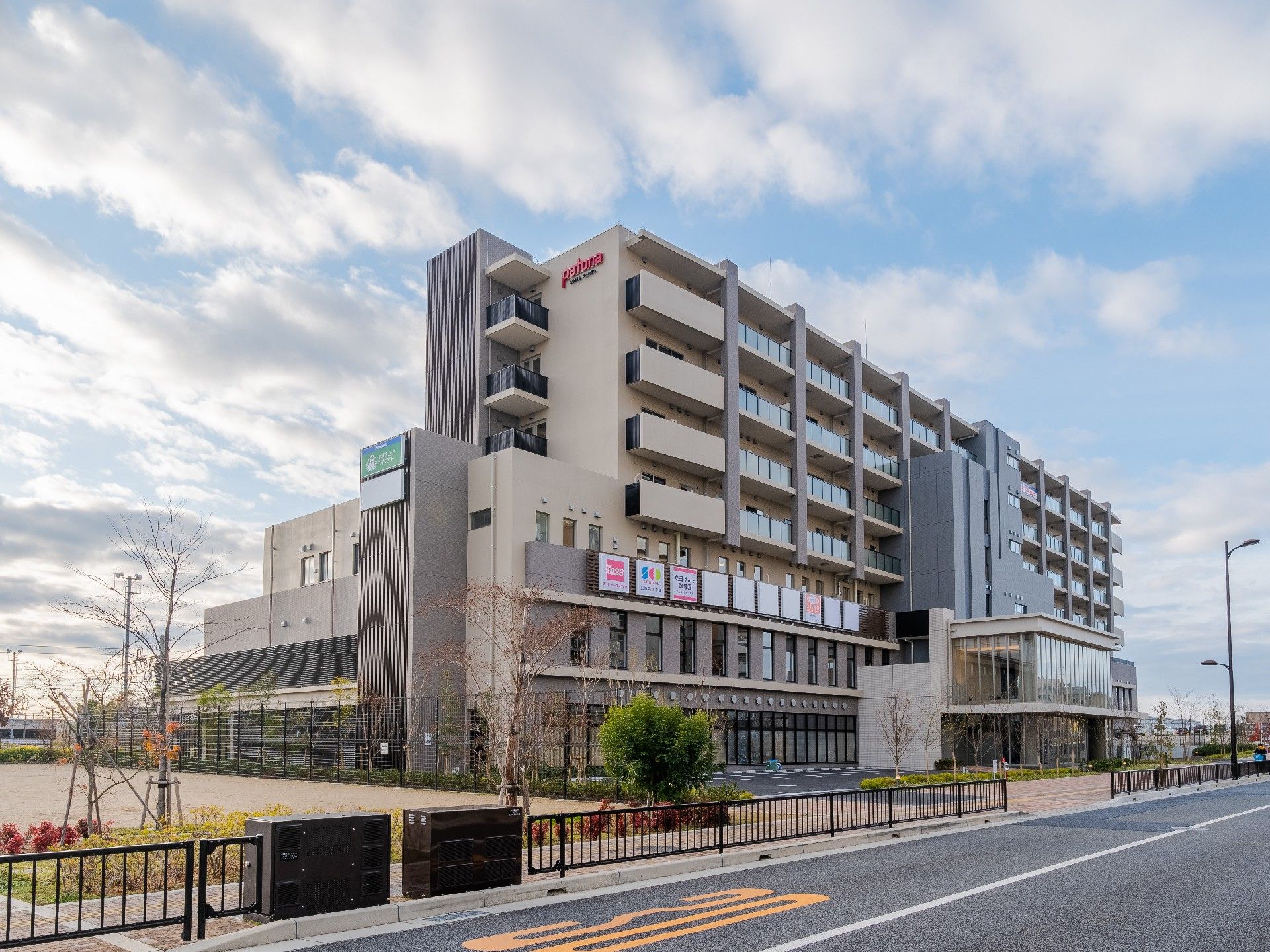 大型のマンションのような外観。周辺には緑が植えられ、道路に面している。