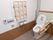 洋式トイレがあり、便座の横と壁に手すりが設置されている。ペーパーホルダーの横にナースコールが設置されている。