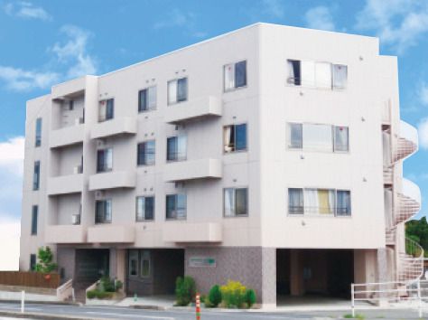 白を基調とした建物は４階建てで、建物の周りには草木が植えられている。日当たりのいい場所に建っている。
