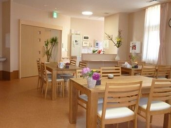 木製の４人掛けのダイニングテーブルが複数置かれた食堂には花や観葉植物が飾られている。