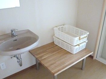 白いかごが置かれたベンチタイプの台が、車いす対応の洗面所のそばに置かれている。