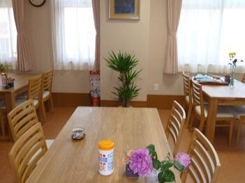 花や観葉植物が飾られている食堂には４人掛けの木製のダイニングテーブルが複数置かれている。