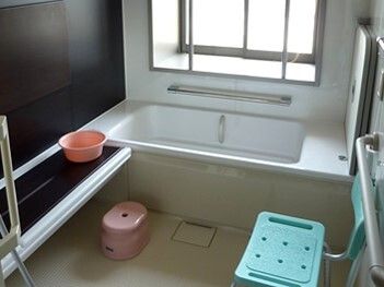白と黒の浴室にはシャワーやシャワーチェアがあり、手すりがたくさん付き、窓もあり明るい。
