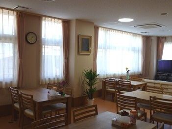 絵画や観葉植物が飾られている食堂には、木製の４人掛けのダイニングテーブルが複数置かれている。
