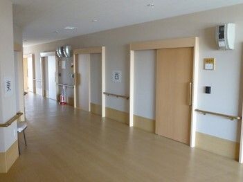 幅の広い廊下には手すりが付き、スライド式のドアが設置された居室が並んでいる。