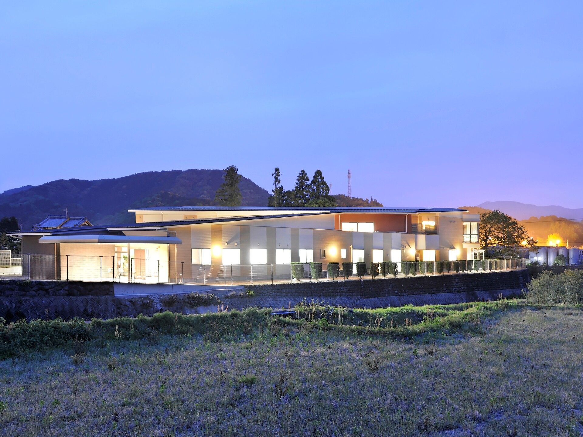 夕暮れ時になりライトアップされた建物。明かりが窓から漏れている様子。