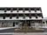 前面部分にベランダが設置されている大きな建物がある。玄関正面には花壇があり、樹木が植えられている。地面は段差がなく舗装されている。
