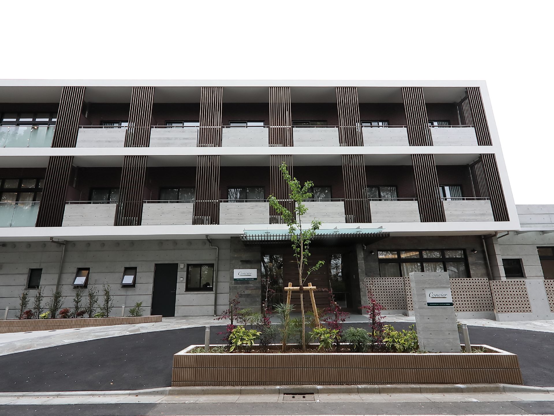 天気が良い日のコンシェール徳丸の外観。鉄骨造の建物、周辺に桜の花