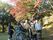 紅葉のきれいな公園への外出を楽しむ入居者とスタッフ。車いすに乗っている入居者の介助をしながら。