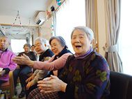 ホームの共有ルームで笑顔でレクリエーションに参加する女性入居者たち。