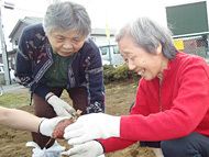 二人の女性入居者が嬉しそうに大きなサツマイモを手にしている。
