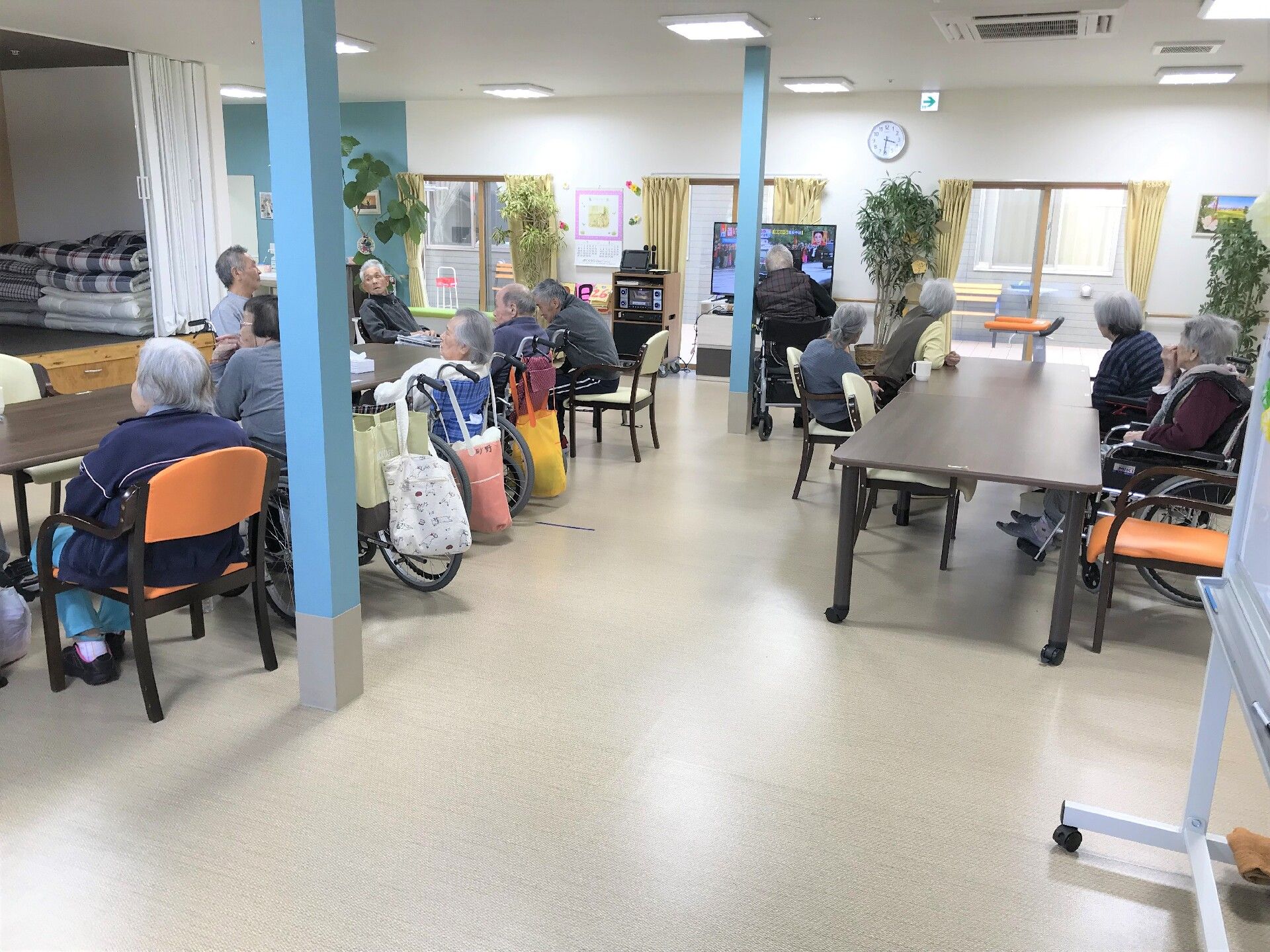 観葉植物がたくさん置かれた食堂には大き目のダイニングテーブルが複数置かれ、入居者がテーブルを囲み、それぞれ好きなことをしている。