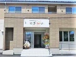 玄関先には屋根が付き、外壁には大きくホーム名が書かれている。階段とスロープの両方が設置されている。