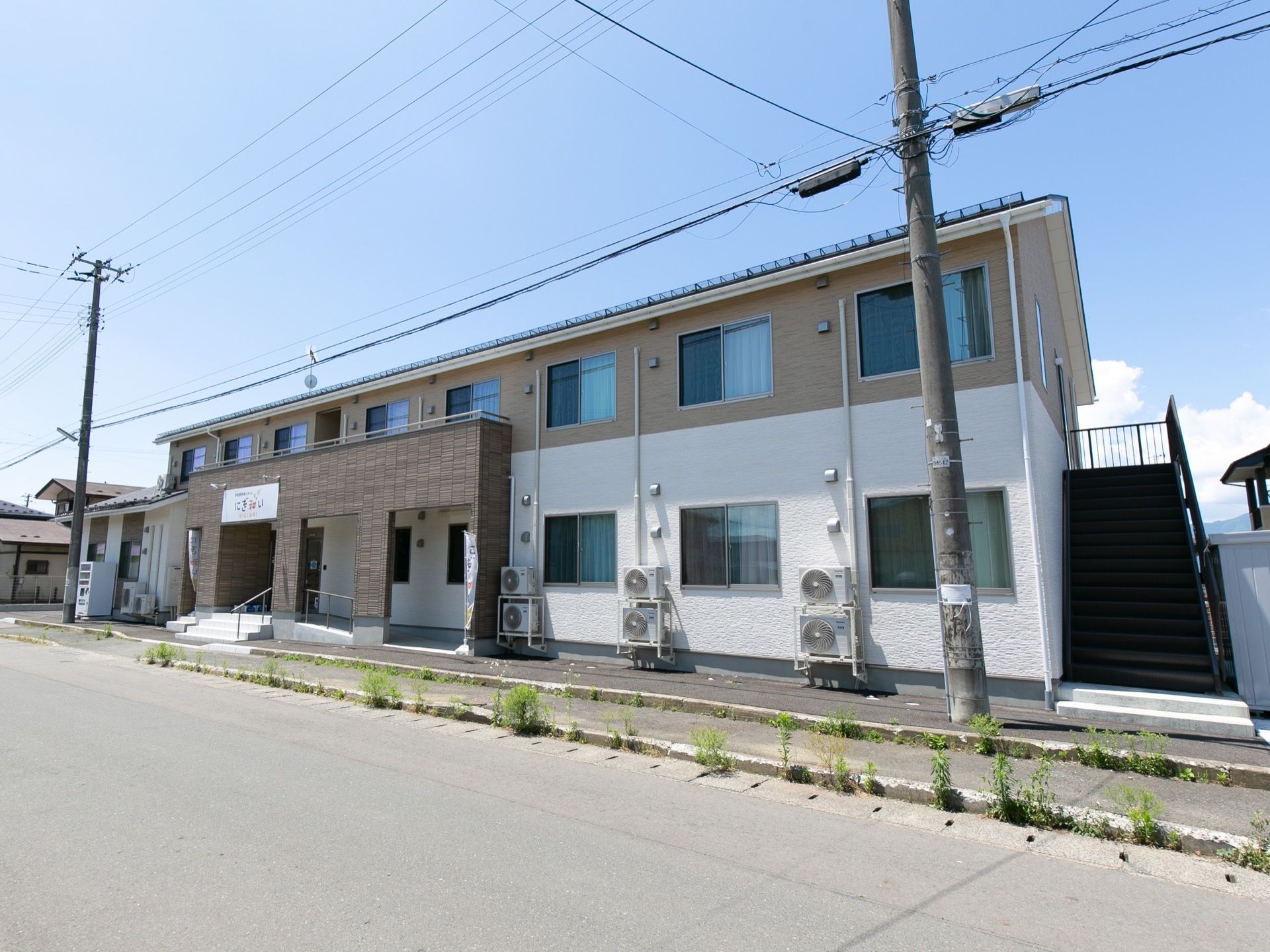 施設は2階建ての集合住宅のような外観である。壁面が白と茶のツートンカラーでおしゃれな雰囲気になっている。