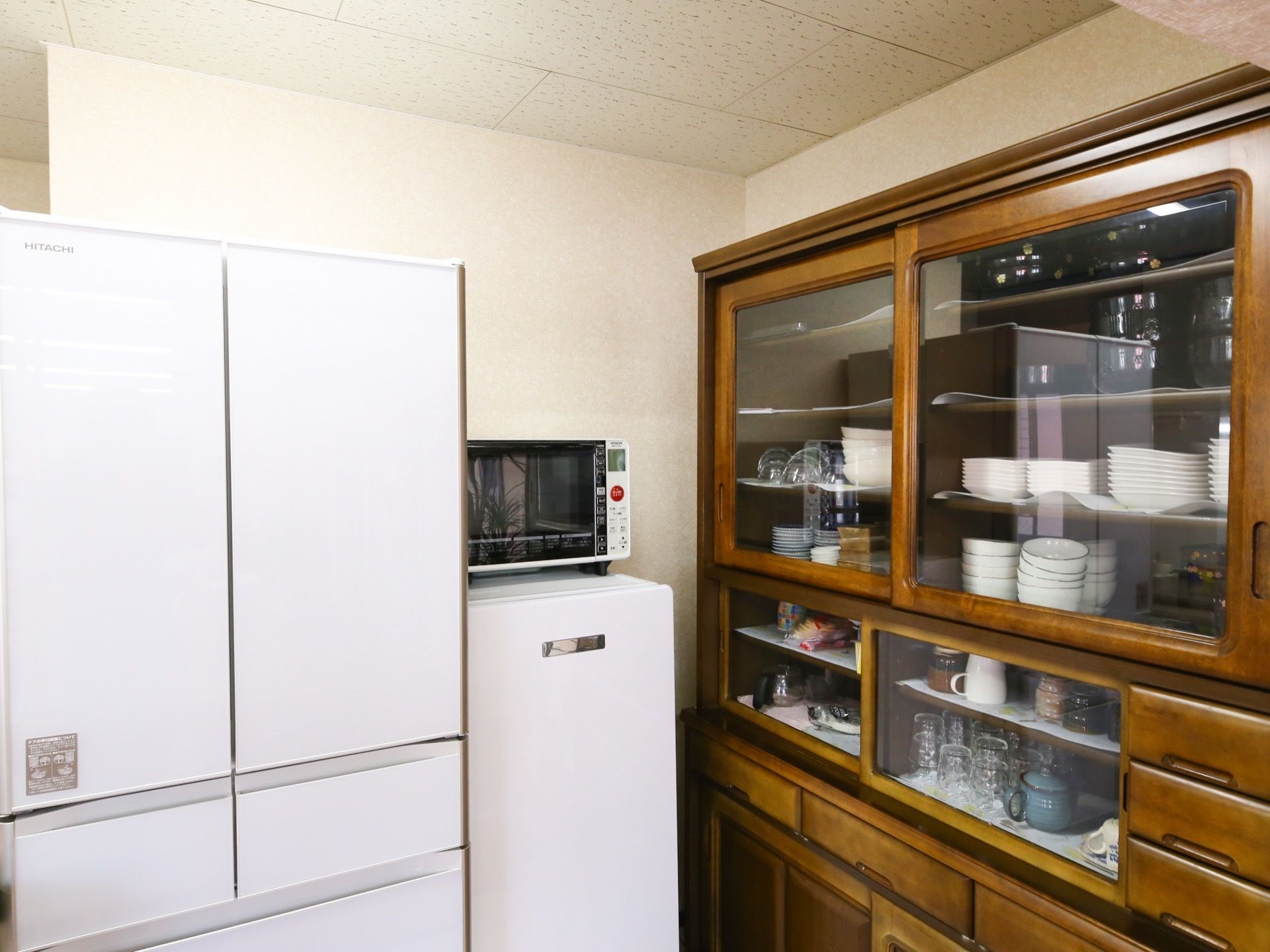 キッチンには、某有名メーカーの両開き式の白い冷蔵庫が設置されている。横には、電子レンジや食器棚が置かれている。