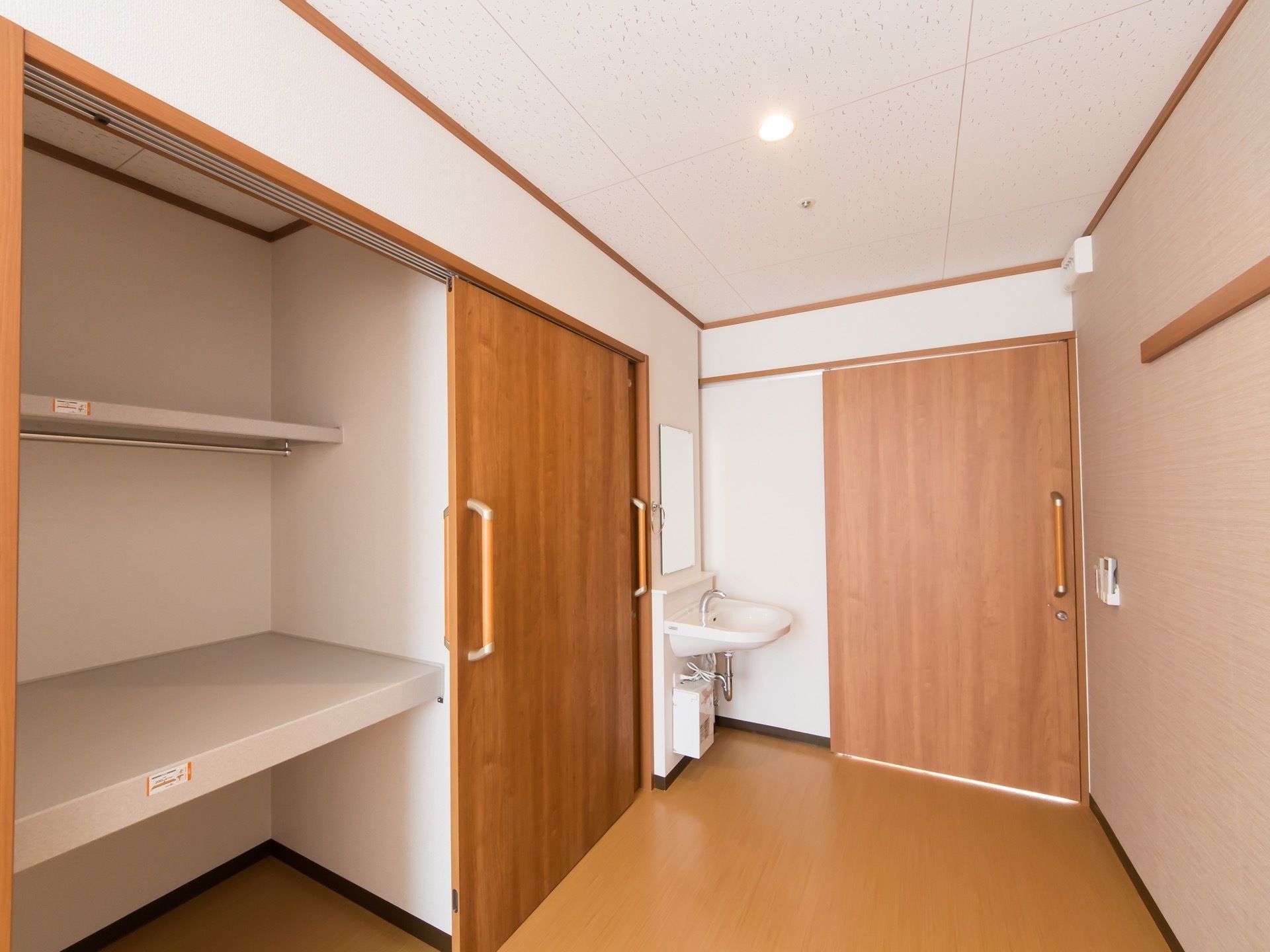 居室に入ってすぐの所に洗面台が設置されている。その左側に、大きな取っ手のある扉がついた収納スペースがある。